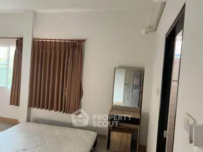 Spacious bedroom with natural light and elegant curtains, featuring a comfortable mattress and stylish vanity.