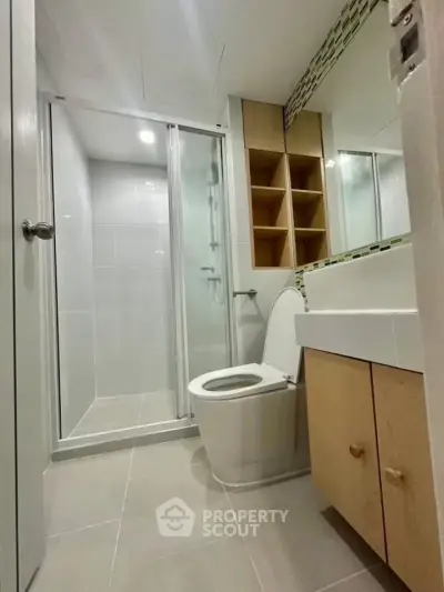 Modern bathroom with glass shower and sleek fixtures in contemporary apartment.