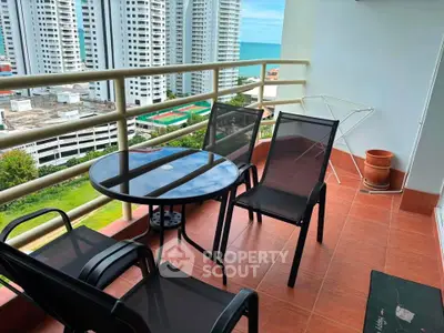 Spacious balcony with ocean view in high-rise apartment, featuring modern outdoor furniture.
