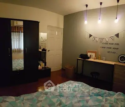 Cozy bedroom with modern decor and ambient lighting, featuring a stylish wardrobe and a functional desk area.