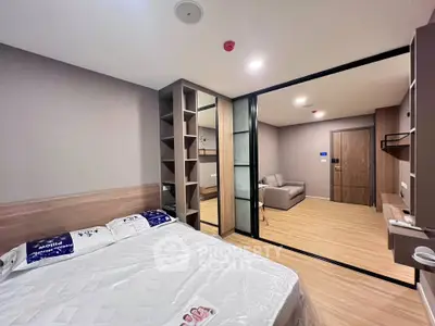 Modern bedroom with sliding glass doors leading to a cozy living area, featuring sleek wooden flooring and stylish decor.