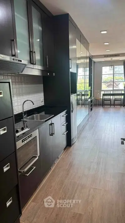 Modern kitchen with sleek black cabinetry and built-in appliances in a bright apartment.