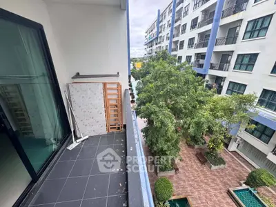 Charming balcony view overlooking lush courtyard in modern apartment complex.