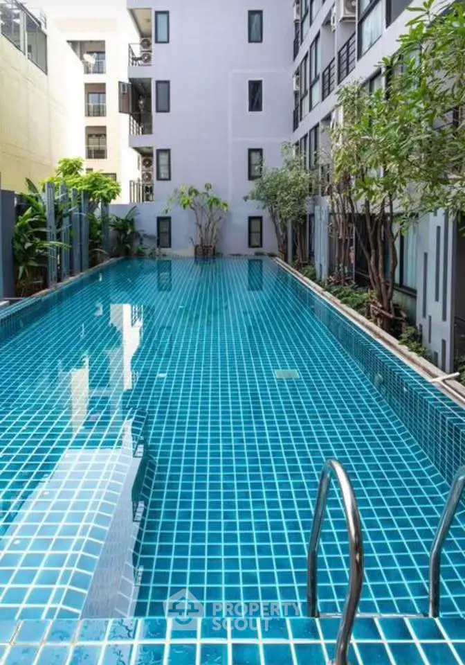 Luxurious apartment complex with a stunning outdoor pool surrounded by lush greenery.