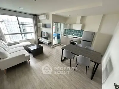 Modern open-plan living room with kitchen, featuring sleek furniture and natural light.