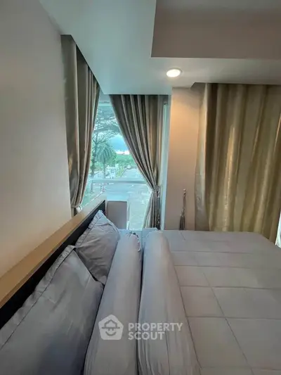 Cozy bedroom with large window offering scenic view and elegant curtains