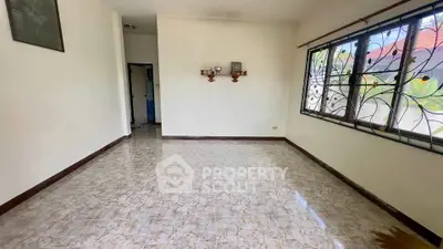 Spacious empty room with tiled floor and decorative window bars in a well-lit home.