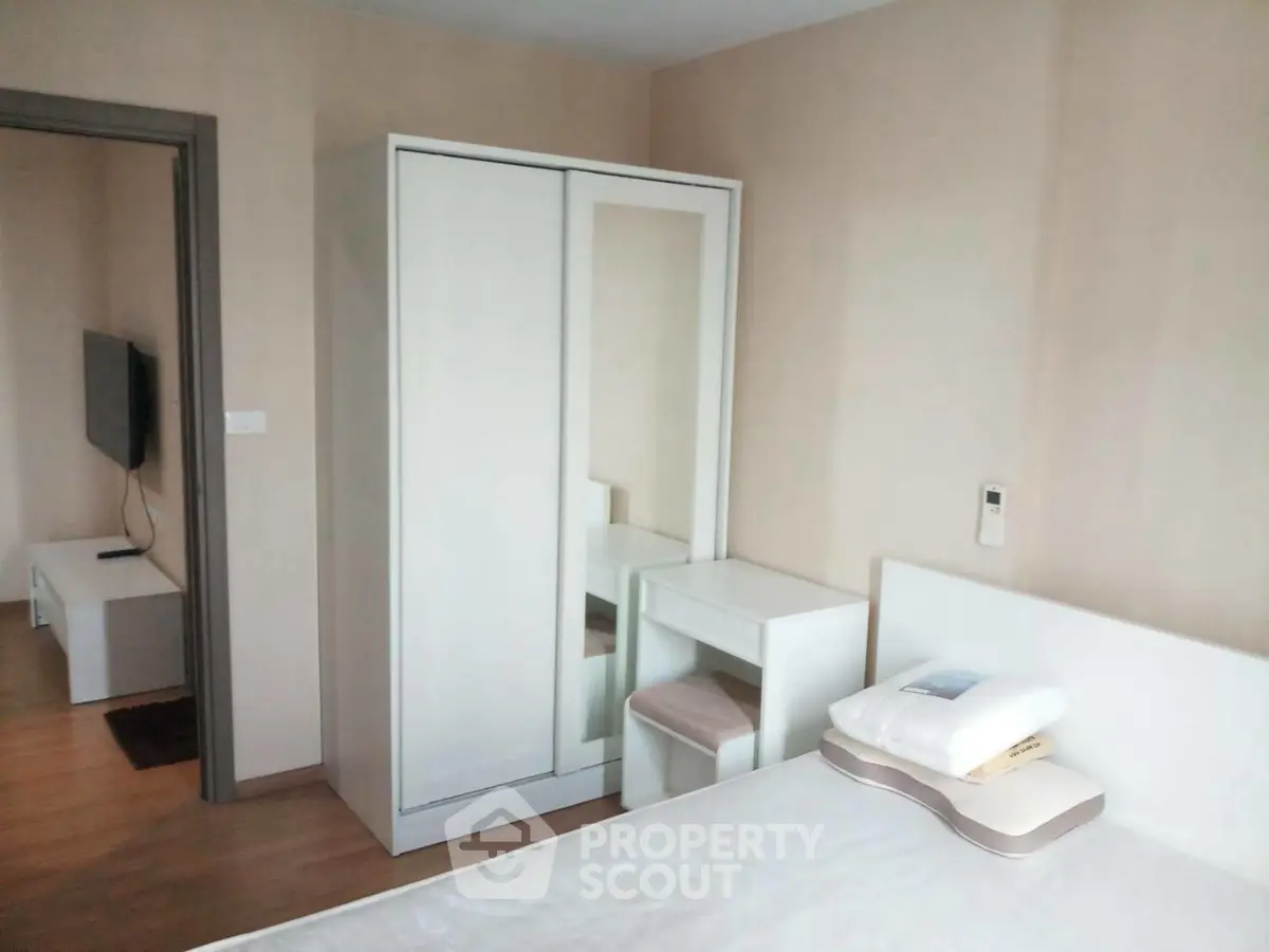 Cozy bedroom with modern white furniture and a glimpse of the living area