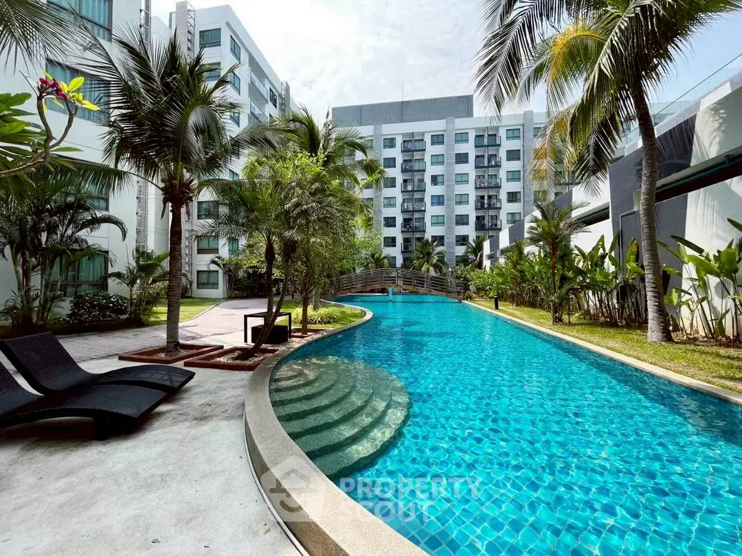 Luxurious apartment complex with stunning pool and lush tropical landscaping.