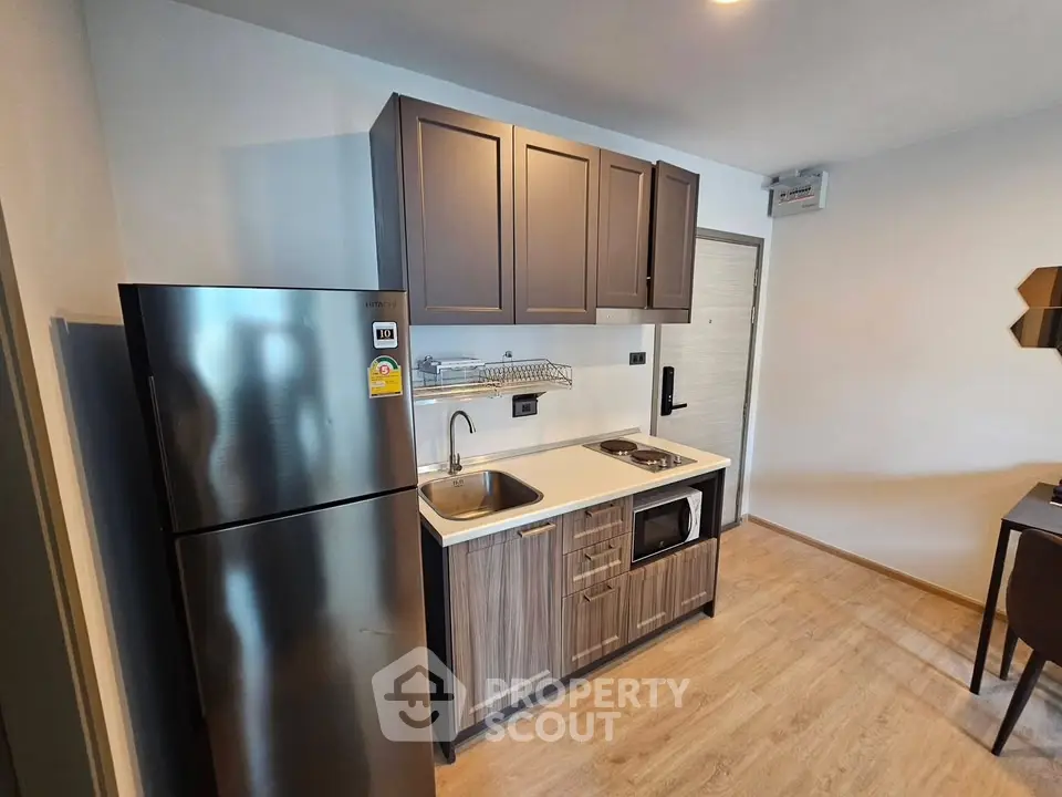 Modern compact kitchen with sleek cabinets and stainless steel fridge in cozy apartment.