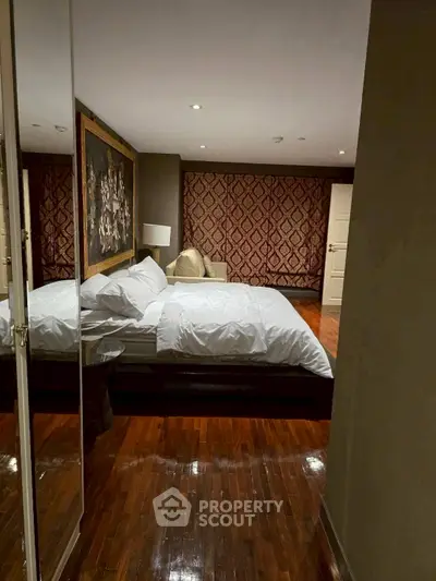 Luxurious bedroom with elegant decor and polished wooden floors, featuring a large bed and stylish wall art.