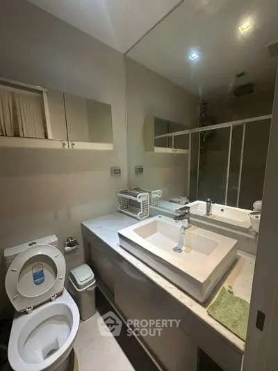 Modern bathroom with sleek fixtures and large mirror, featuring a spacious shower area and elegant sink.
