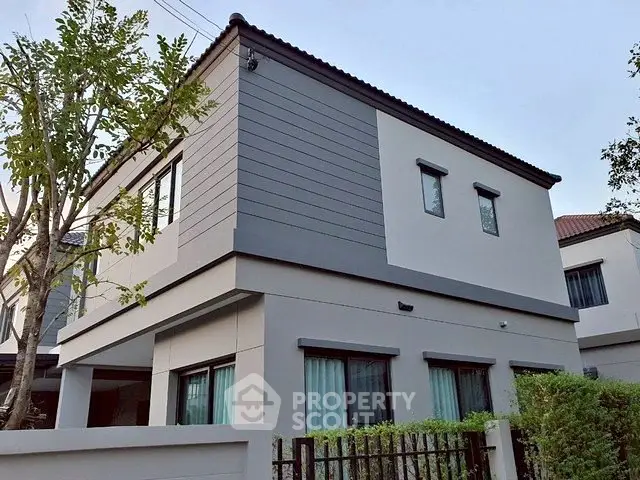 Modern two-story house with sleek design and large windows in a suburban neighborhood.