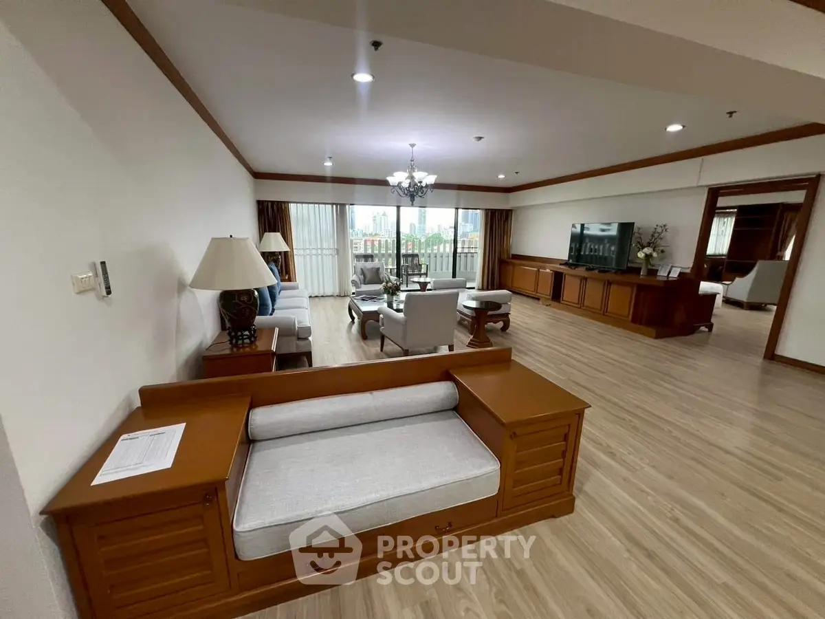 Spacious living room with elegant wooden furniture and large windows offering natural light.