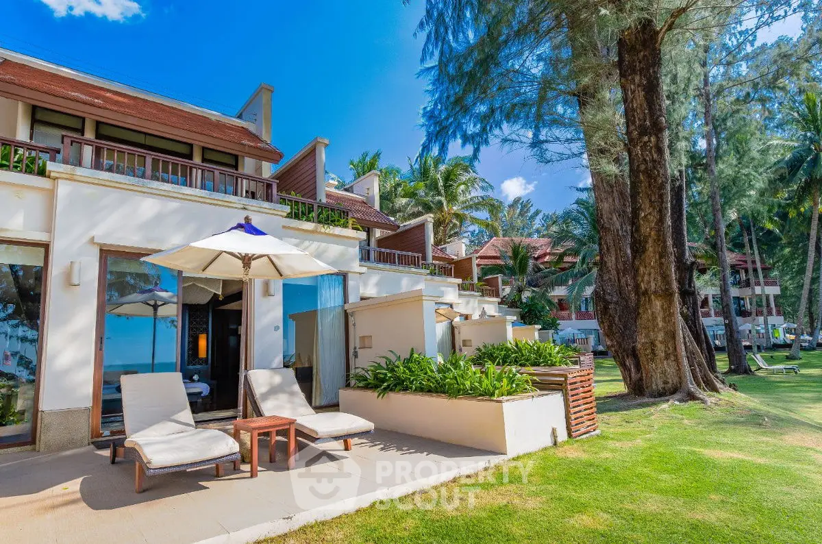Luxurious beachfront villa with private patio and lush greenery, perfect for serene coastal living.