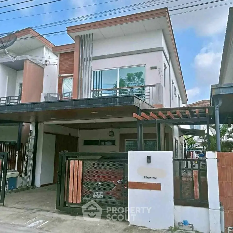 Modern two-story house with carport and gated entrance in suburban neighborhood.