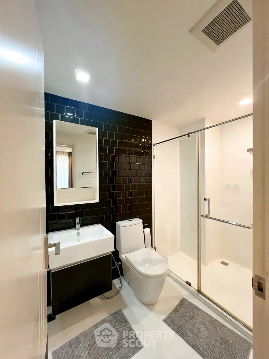 Modern bathroom with sleek black tiles and glass shower enclosure