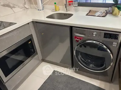 Modern kitchen with integrated appliances including a washing machine and microwave, sleek countertops, and stylish decor.