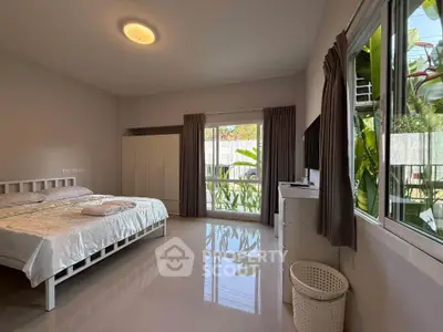 Spacious bedroom with large windows and garden view, featuring modern decor and ample natural light.