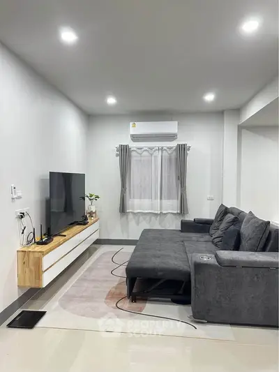 Modern living room with sleek furniture and wall-mounted TV, perfect for relaxation.