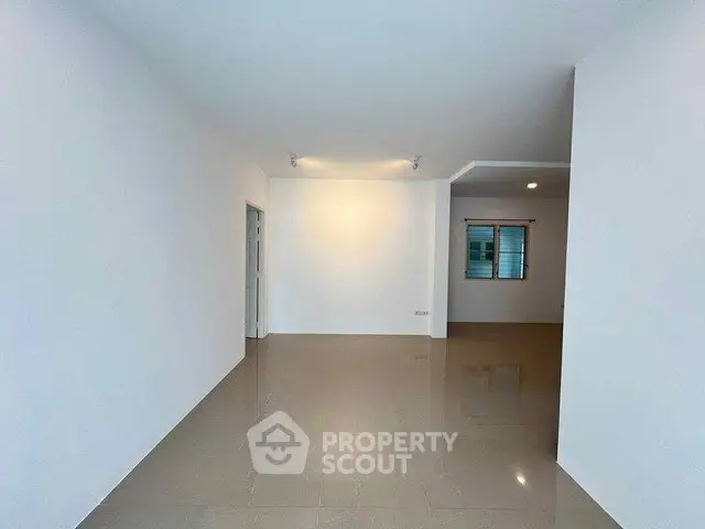 Spacious empty room with glossy tiled floor and white walls, perfect for customization.