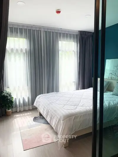 Cozy bedroom with large windows and modern decor, perfect for relaxation and comfort.