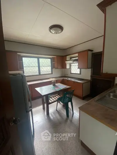 Cozy kitchen with wooden cabinets and natural light, featuring a gas stove and dining area.