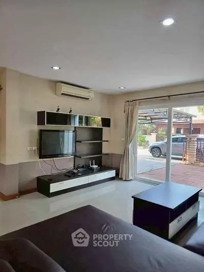 Modern living room with sleek entertainment center and large sliding glass doors leading to patio.
