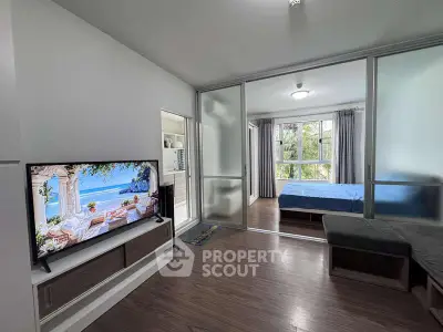 Modern living room with TV and view into cozy bedroom