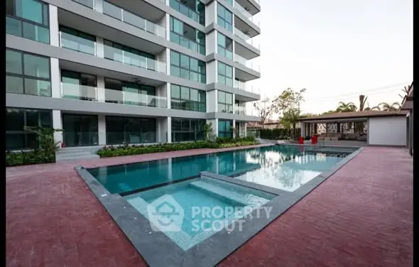 Modern apartment building with luxurious pool and spacious deck area.