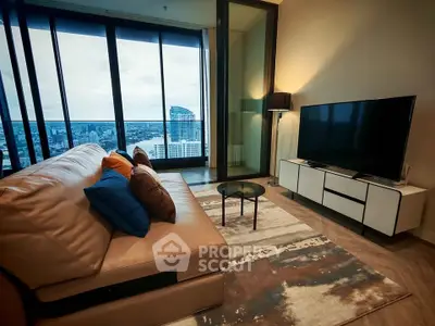 Luxurious living room with stunning city view from high-rise balcony, featuring modern furniture and large TV.