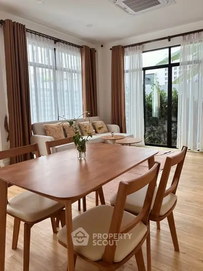Elegant living room with wooden dining set and large windows for natural light.
