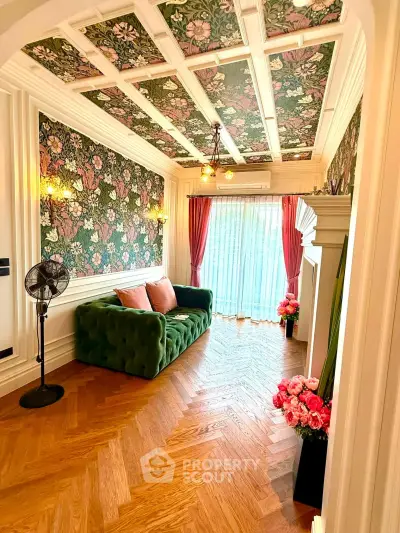 Charming living room with floral wallpaper, elegant ceiling design, and cozy green sofa.