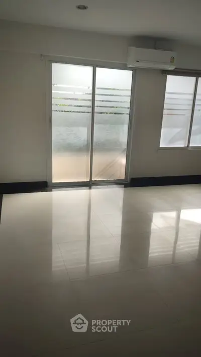 Spacious empty room with large windows and glossy tiled floor, perfect for customization.