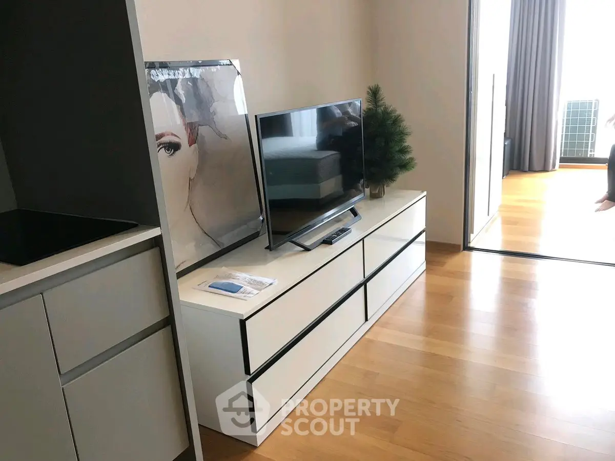Modern living room with sleek TV stand and hardwood floors, featuring contemporary decor.