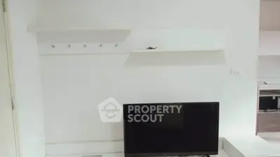 Minimalist living room with wall-mounted TV and shelves in modern apartment.