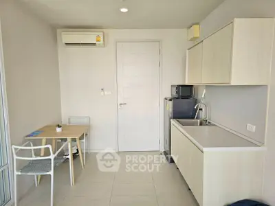 Modern compact kitchen with dining area and air conditioning in a cozy apartment.