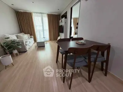 Modern living room with cozy seating and dining area, featuring elegant decor and natural light.