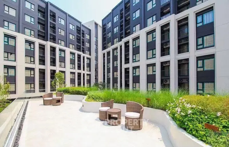 Modern apartment building with stylish outdoor seating area and lush greenery.