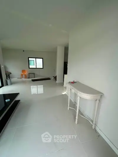 Spacious modern living area with sleek white flooring and minimalist decor.