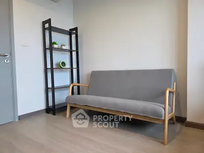 Modern minimalist living room with sleek gray sofa and stylish shelving unit.