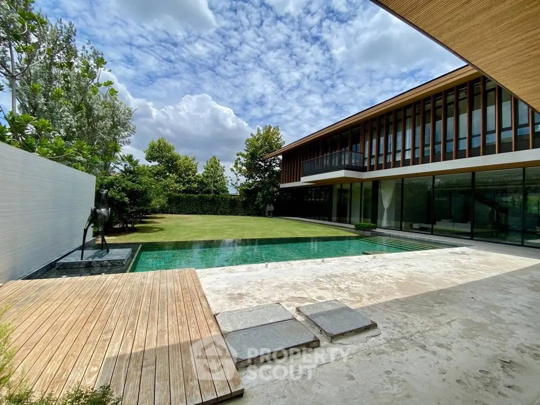 Luxurious modern home with expansive pool and lush garden under a vibrant sky.