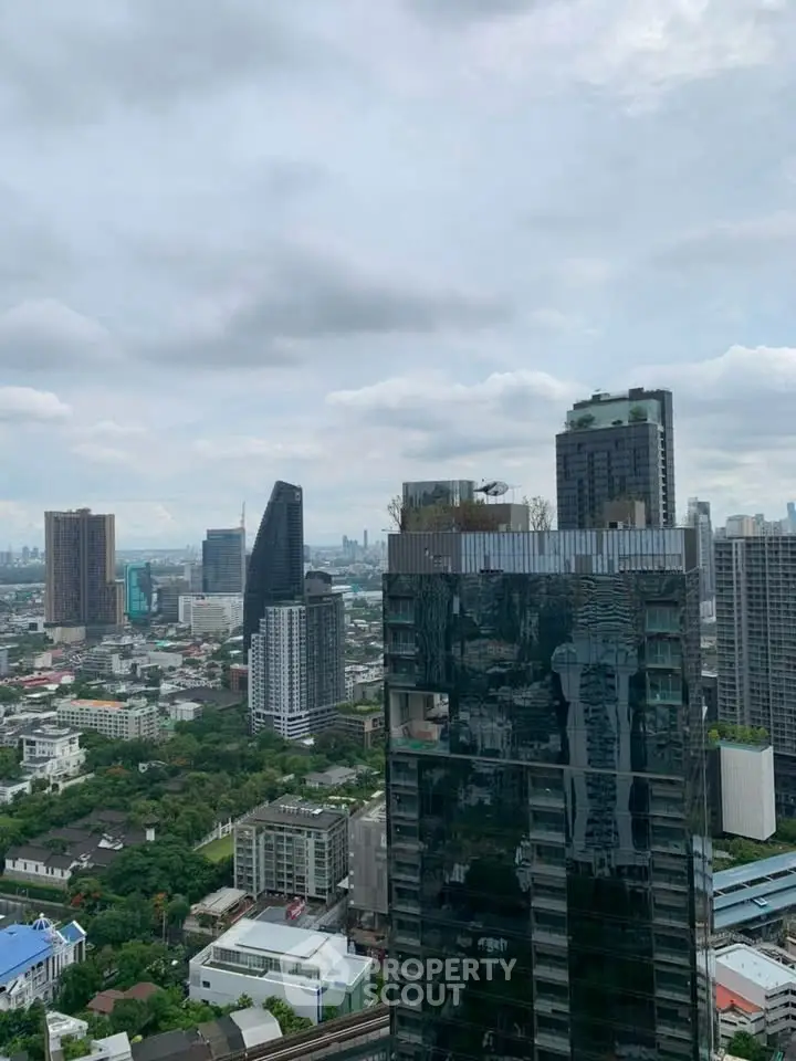 Stunning cityscape view from a high-rise building showcasing urban skyline and lush greenery.