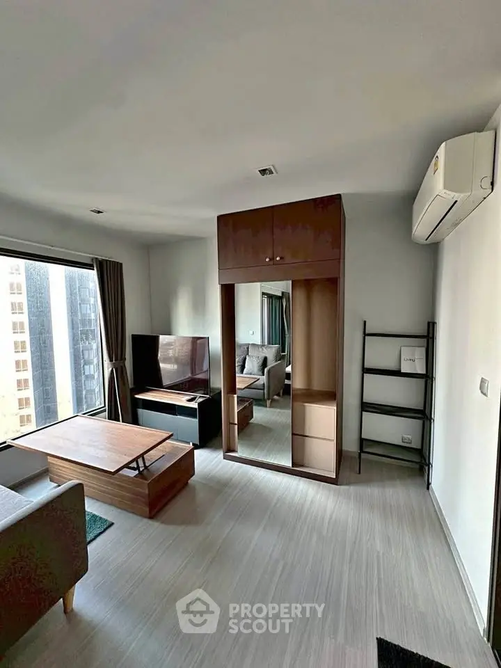 Modern living room with sleek furniture and large windows in a high-rise apartment.