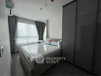 Modern bedroom with large window and sleek wardrobe in a stylish apartment.