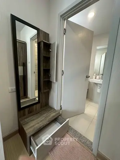 Modern bathroom entrance with stylish wooden storage and mirror, showcasing sleek design and functionality.