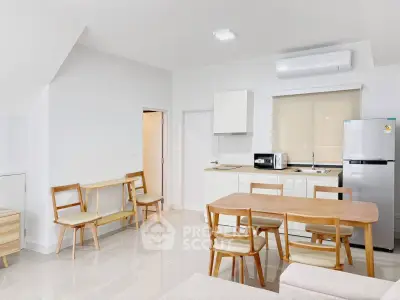 Modern open-layout kitchen and dining area with sleek appliances and minimalist furniture.