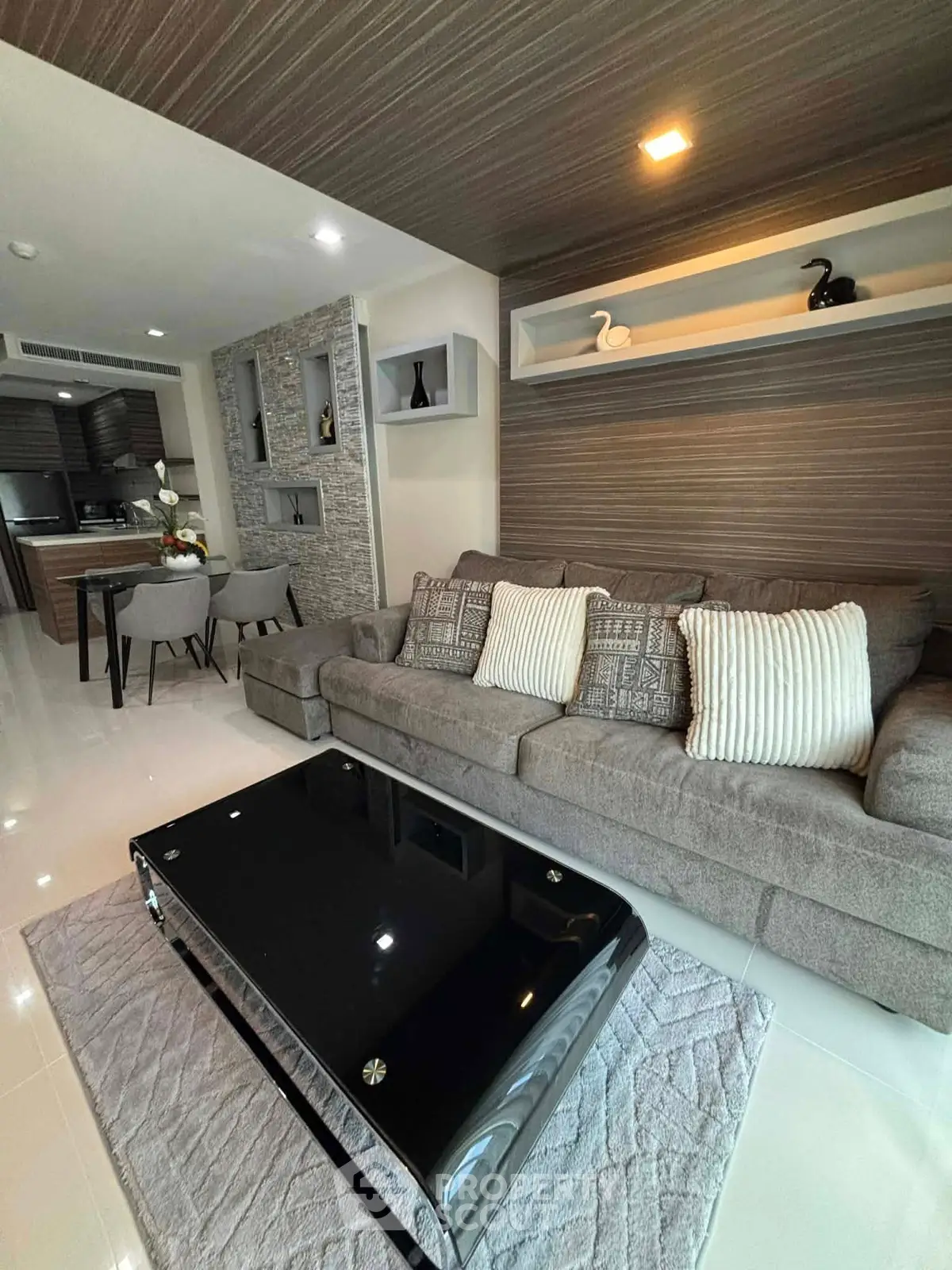 Modern living room with stylish decor and open kitchen layout, featuring a sleek black coffee table and cozy sofa.