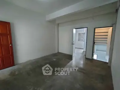 Spacious empty room with concrete floor and open doors, ideal for customization.