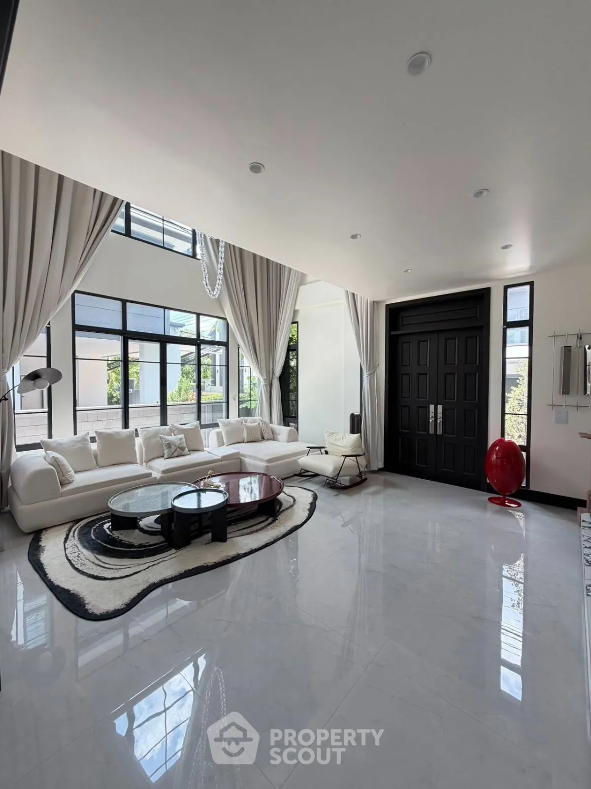 Luxurious modern living room with high ceilings, elegant decor, and large windows offering abundant natural light.